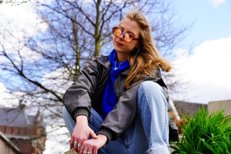 Cool meisje met zonnebril en blauwe hoodie aan, poserend voor de Mezz Breda.