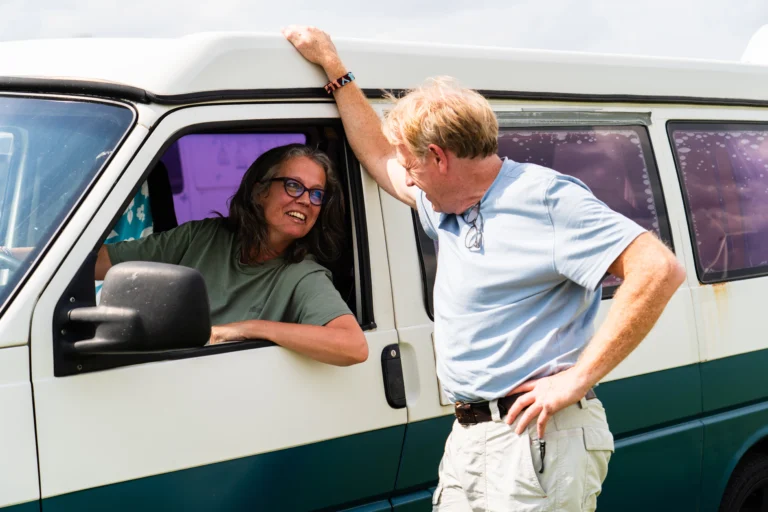 Man en vrouw aan het lachen door het raam van een busje.