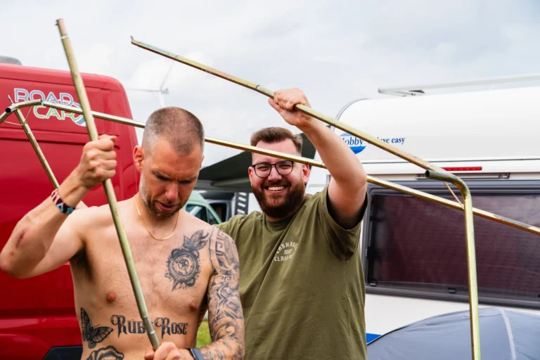 Mannen met tentstokken in de weer.